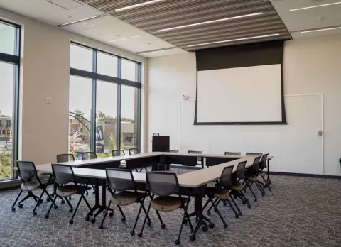 Marion Public Library's Boardroom setup, including tables and chairs, projector and screen, and whiteboard.