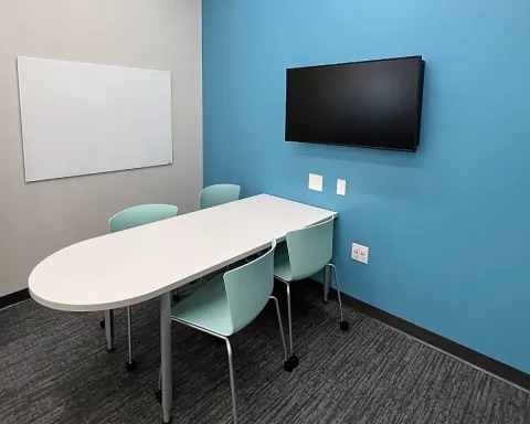Study room with table, chairs, whiteboard, and TV screen