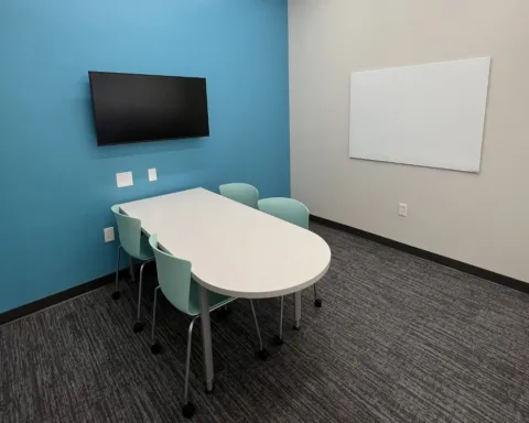 Study room with table, chairs, whiteboard, and TV screen