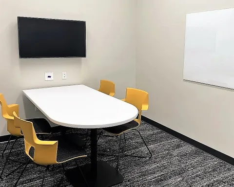 Study room with table, chairs, whiteboard, and TV screen