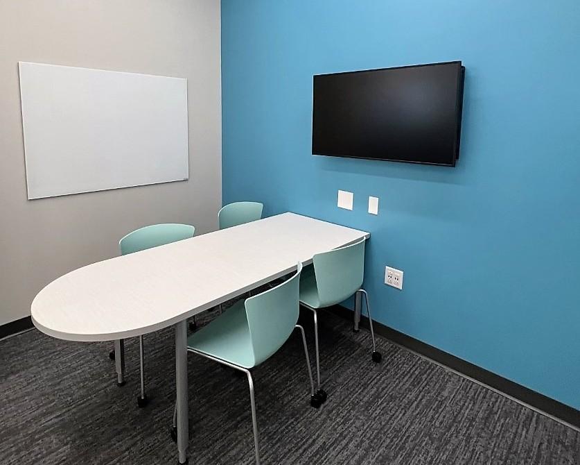 Study room with table, chairs, whiteboard, and TV screen
