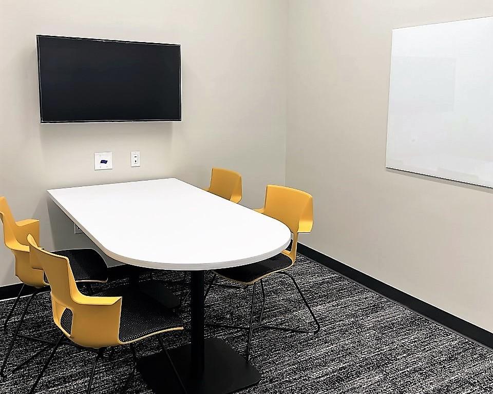 Study room with table, chairs, whiteboard, and TV screen